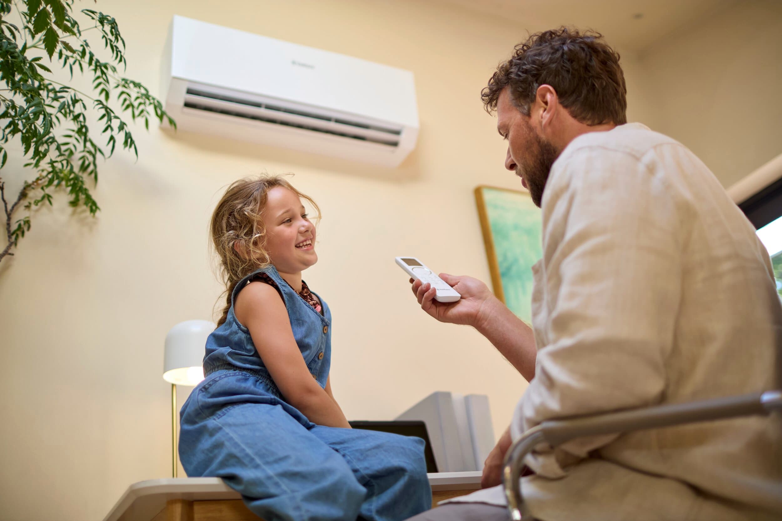 Un padre y su hija encendiendo su nuevo aire acondicionado Vaillant con el control remoto.