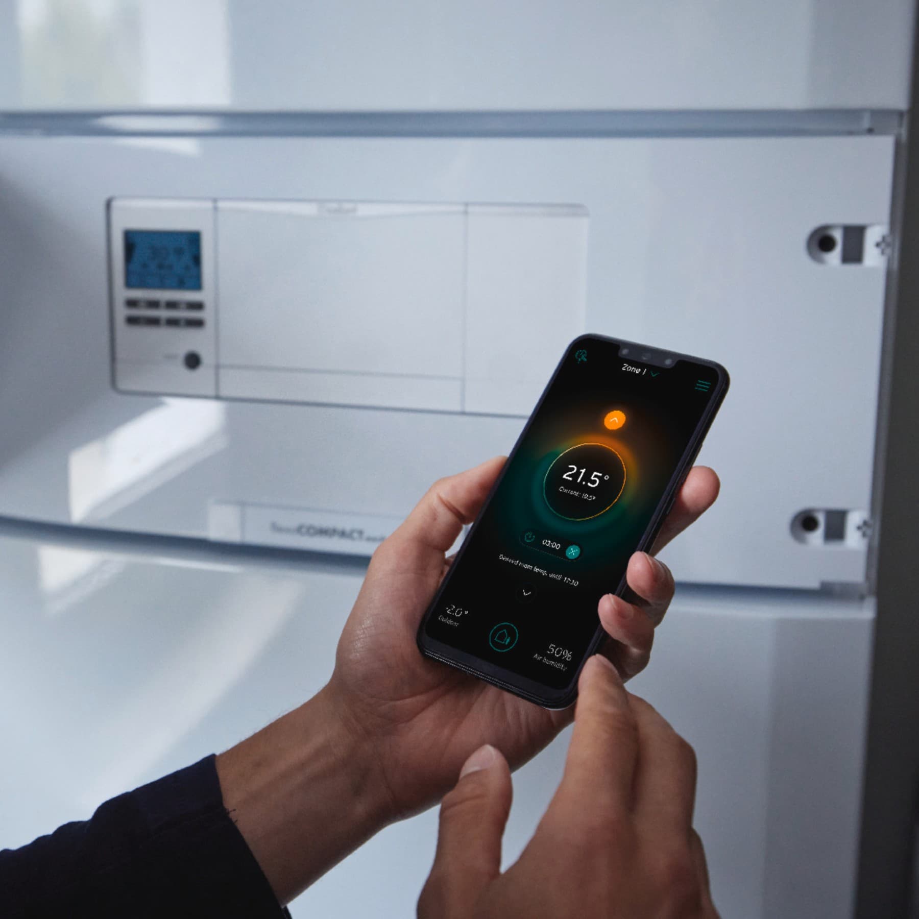 Una persona sosteniendo un smartphone frente a un dispositivo Vaillant.