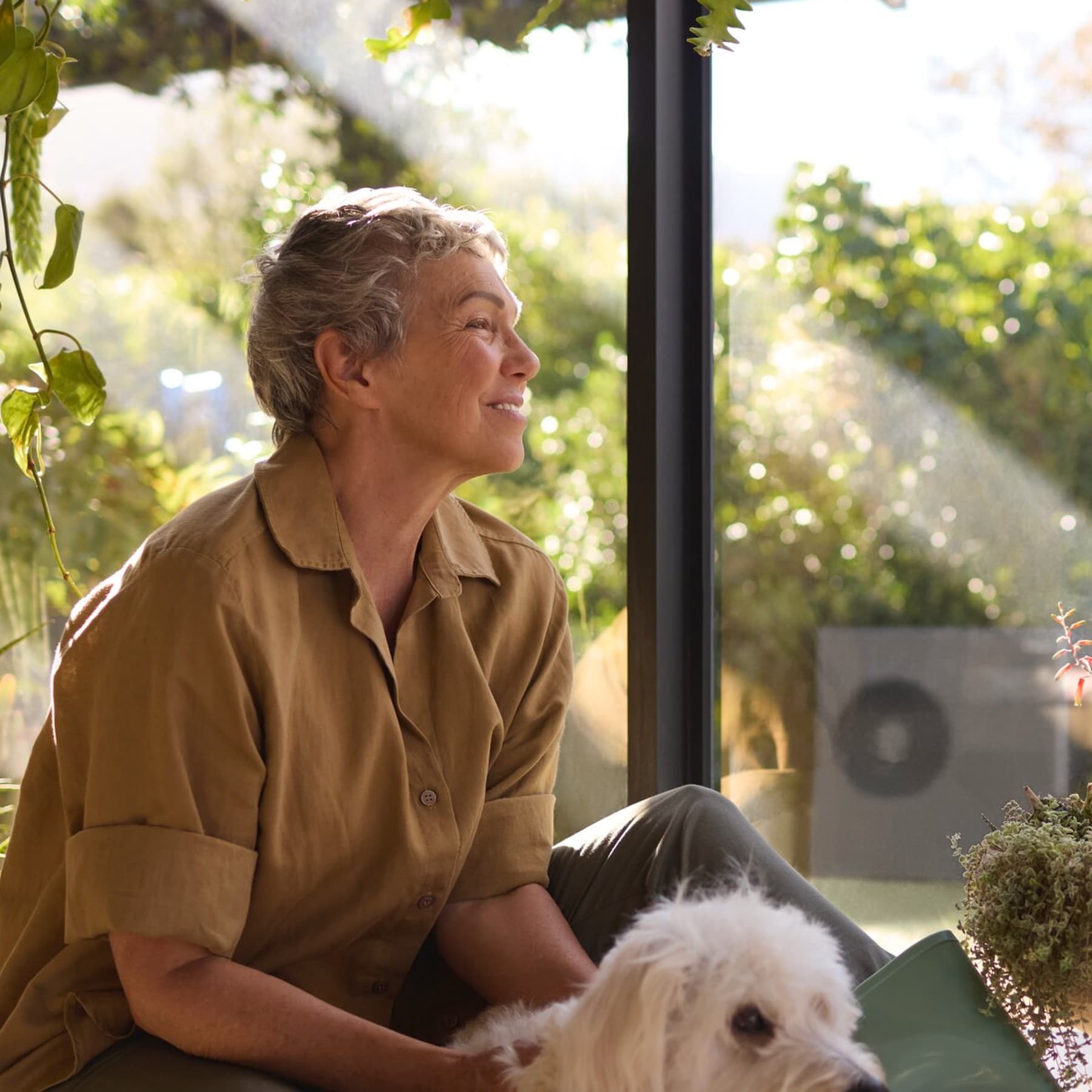 Una mujer sentada junto a su perro junto a la ventana