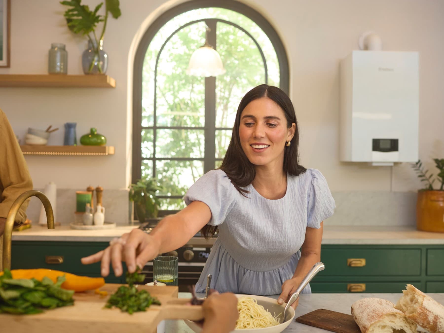 Mujer cocinando en la cocina, con una caldera de gas visible al fondo.