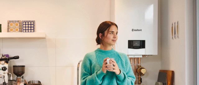 Mujer en su cocina tomando un cafe y detrás, su caldera ecoTEC exclusive